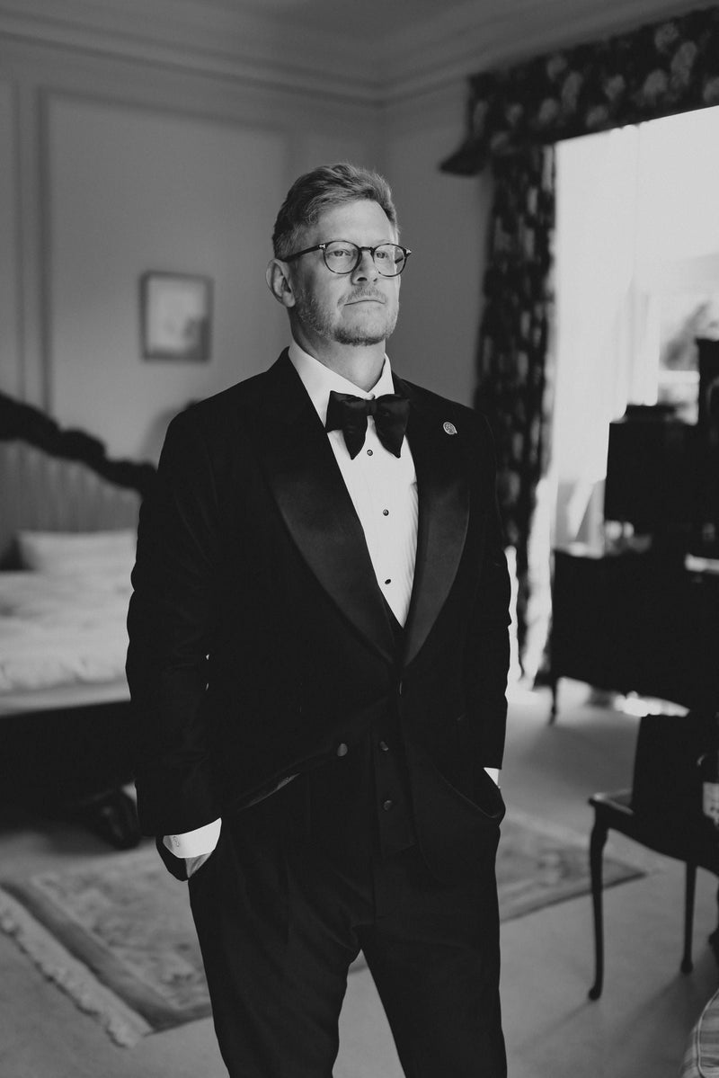Client wearing a tailored black dinner suit and bow tie in a softly lit interior
